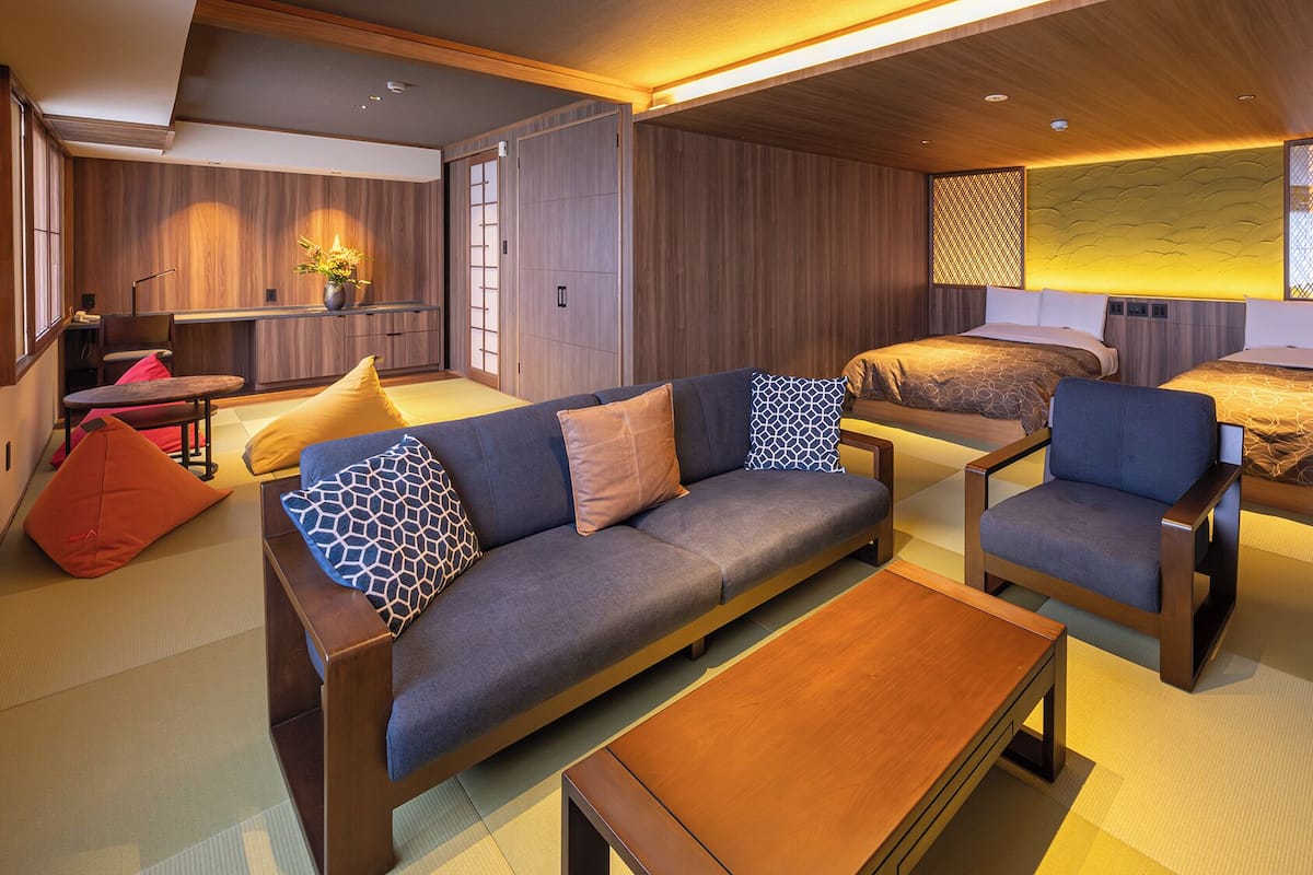 Une chambre d’hôtel moderne avec un canapé, des fauteuils, une petite table et un lit.
