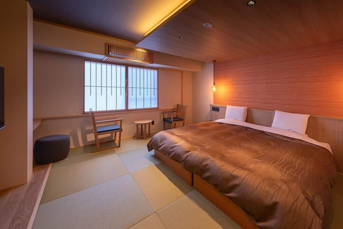 A modern bedroom with a large bed, a desk, and a chair.