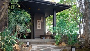 A traditional Japanese-style building with a stone pathway leading to a covered entrance.