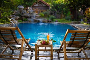 A poolside area with two wooden lounge chairs and a small table with fruit and a drink. - Ninh Binh Family Homestay (Tay Hoa Lu)