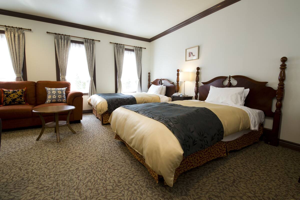 A hotel room with two beds, a sofa, a small table, and a lamp.