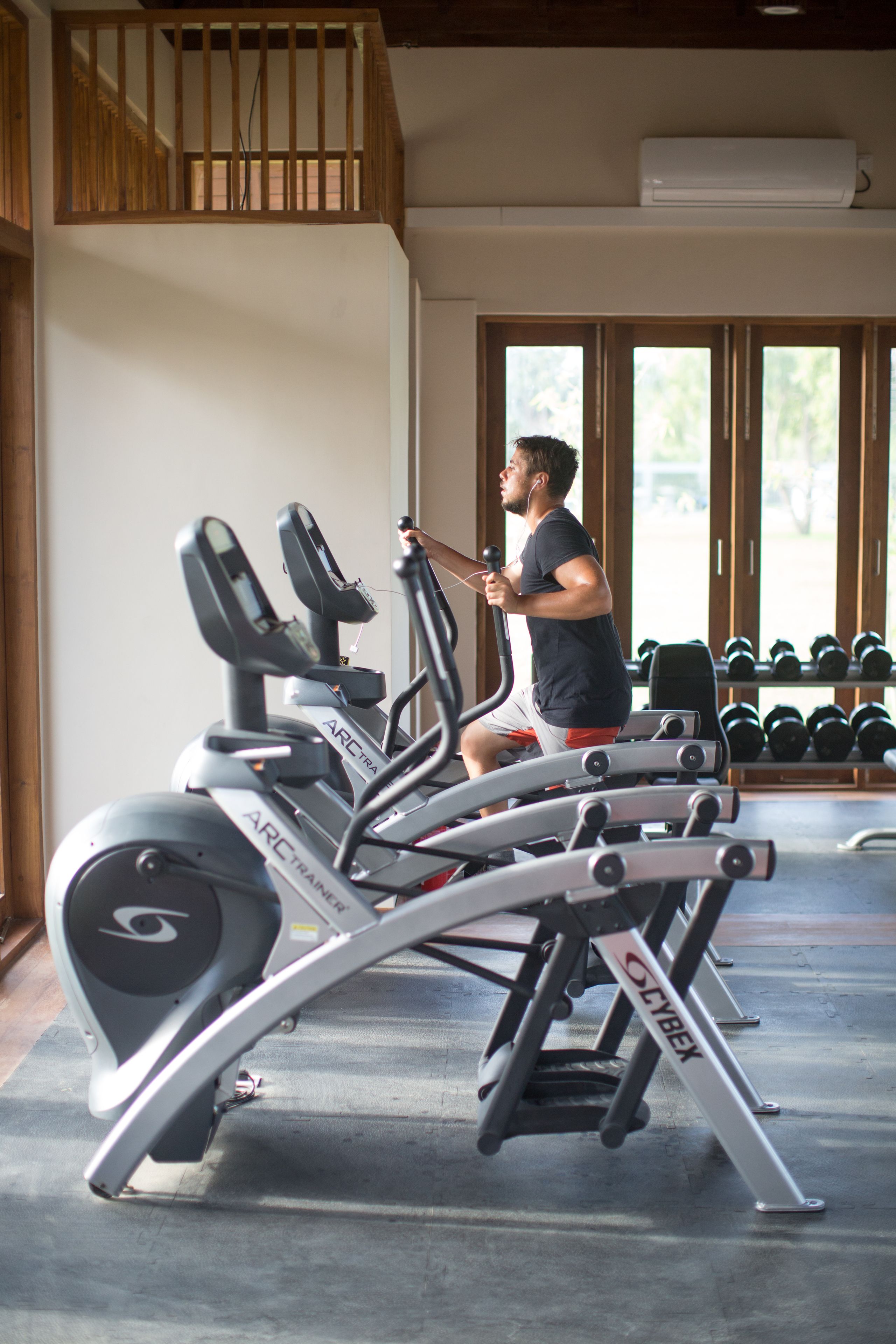 A gym with cardio machines, dumbbells, and a staircase.