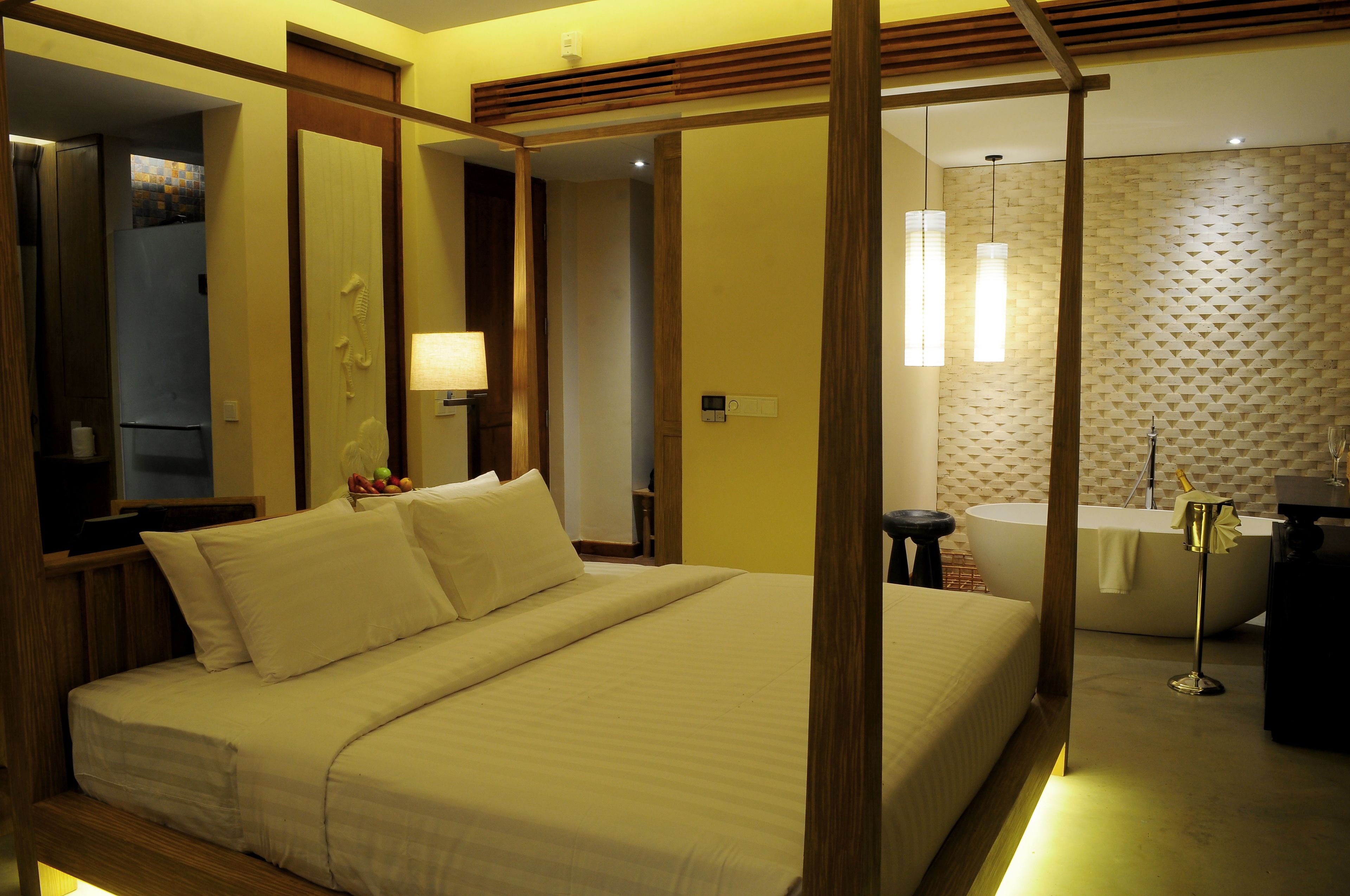 Quarto de hotel com uma cama grande, uma banheira e uma toucador com espelho.