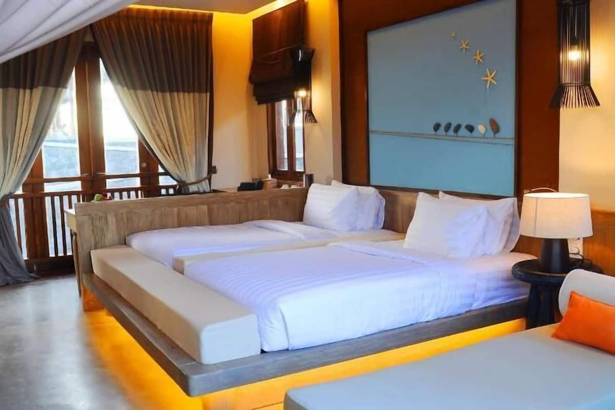 Ein Hotelzimmer mit einem großen Bett, einer Couch, einem Fernseher und Blick ins Freie.