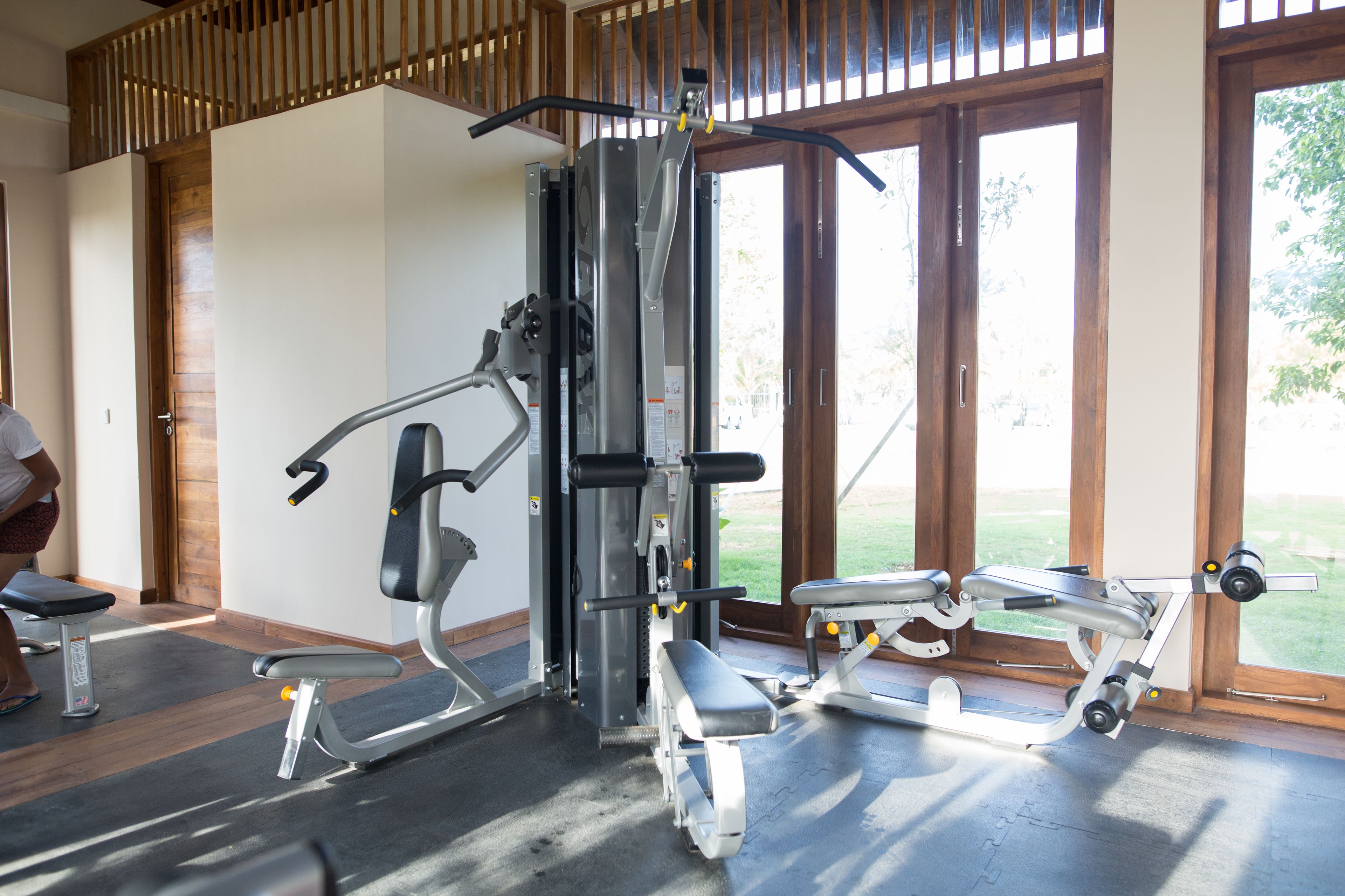 Une salle de sport équipée de matériel d’exercice, dotée de grandes fenêtres et d’un plafond en bois.