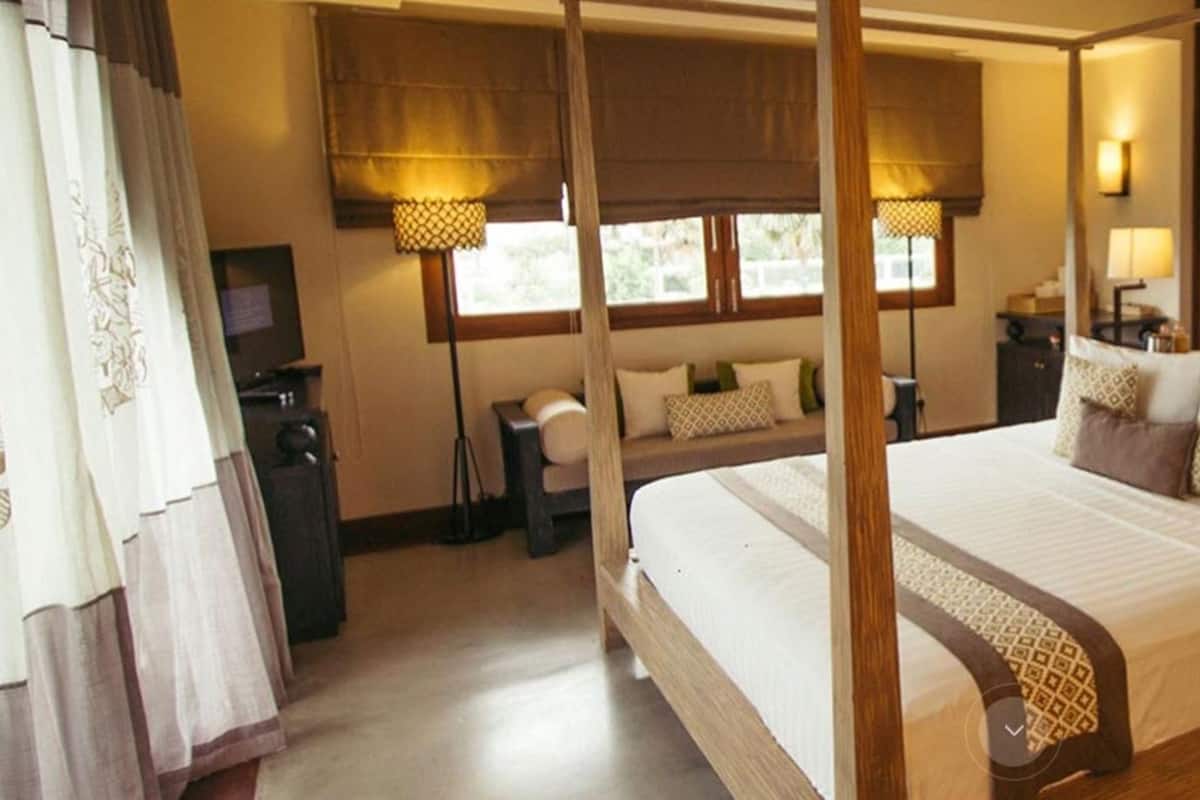 Ein Himmelbett mit Holzrahmen, ein Nachttisch, eine Lampe und ein Spiegel.