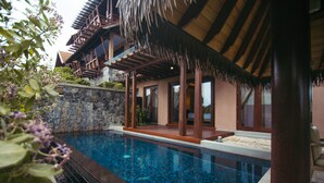A poolside area with a stone wall, wooden deck, and a thatched roof structure. - Anantaya Resort and Spa Passikudah (Pasikuda)