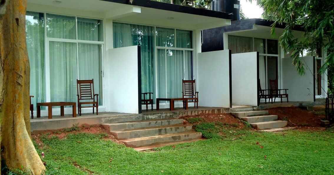 A modern building with a covered porch, steps leading to a door, and a tree in the foreground.