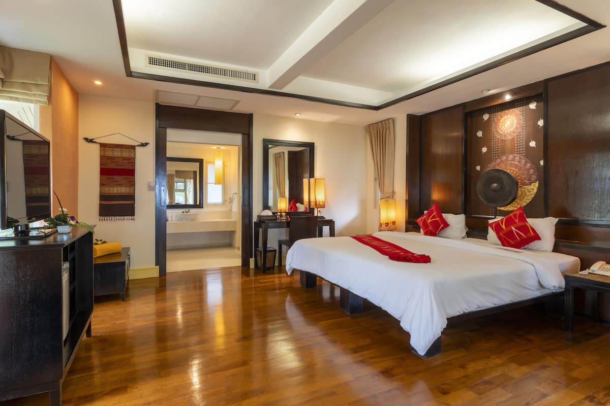 A hotel room with a large bed, a desk, a chair, and a mirror.