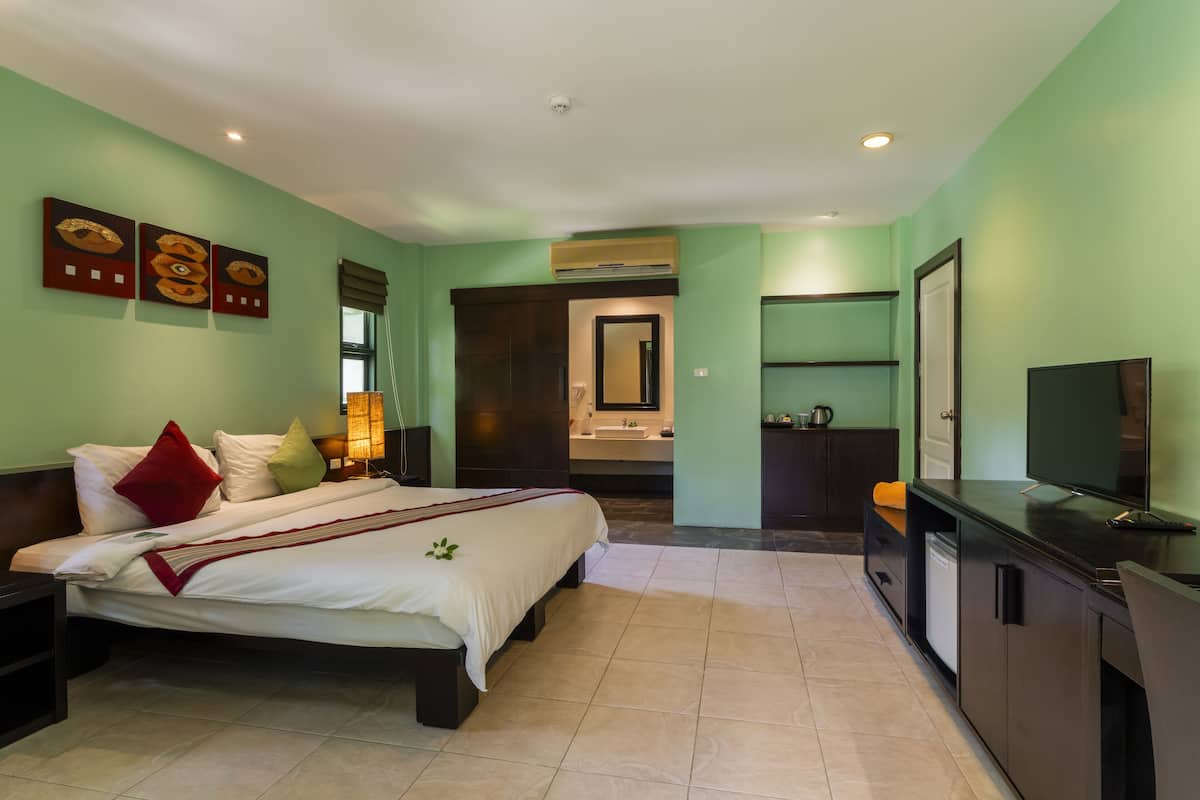 A hotel room with a bed, bedside table, TV, and a bathroom visible through an open door.