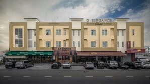Un hotel de fachada moderna, varios pisos y un estacionamiento frente a él.
