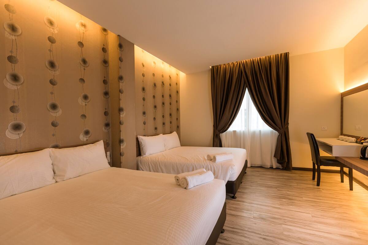A hotel room with two beds, a desk, and a large mirror.