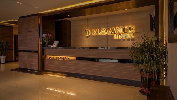 Una mesa de recepción con un cartel que dice "DELEGANCE HOTEL" y un área de recepción.