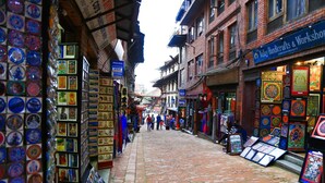 Una calle estrecha flanqueada por tiendas, incluyendo una de artesanías y un taller.