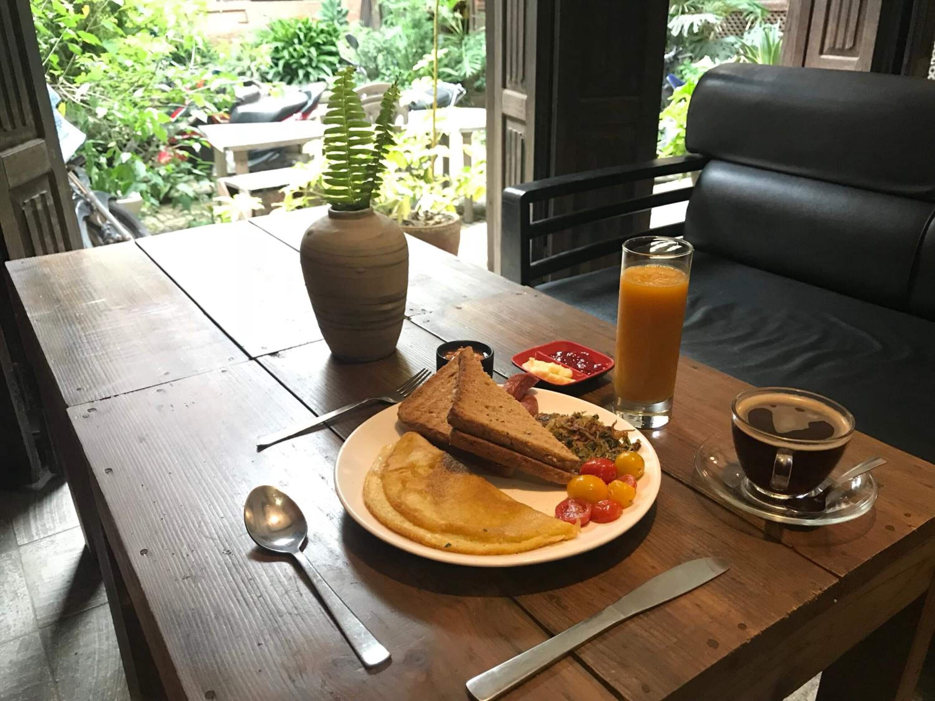 Ein Frühstückstisch mit Toast, Obstteller, Glas Orangensaft und Kaffeetasse.