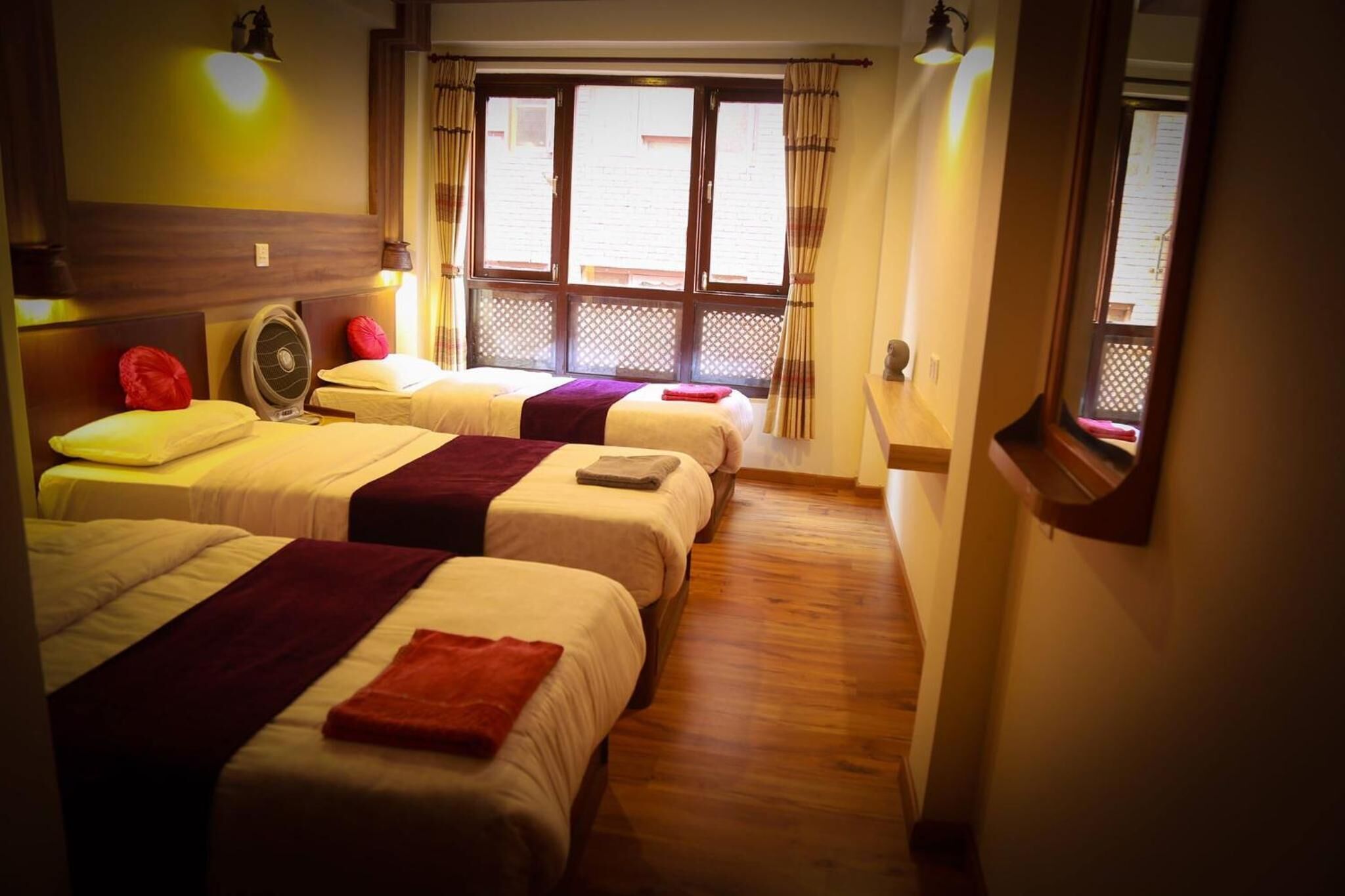 Habitación de hotel con dos camas, un ventilador y una ventana con cortinas.