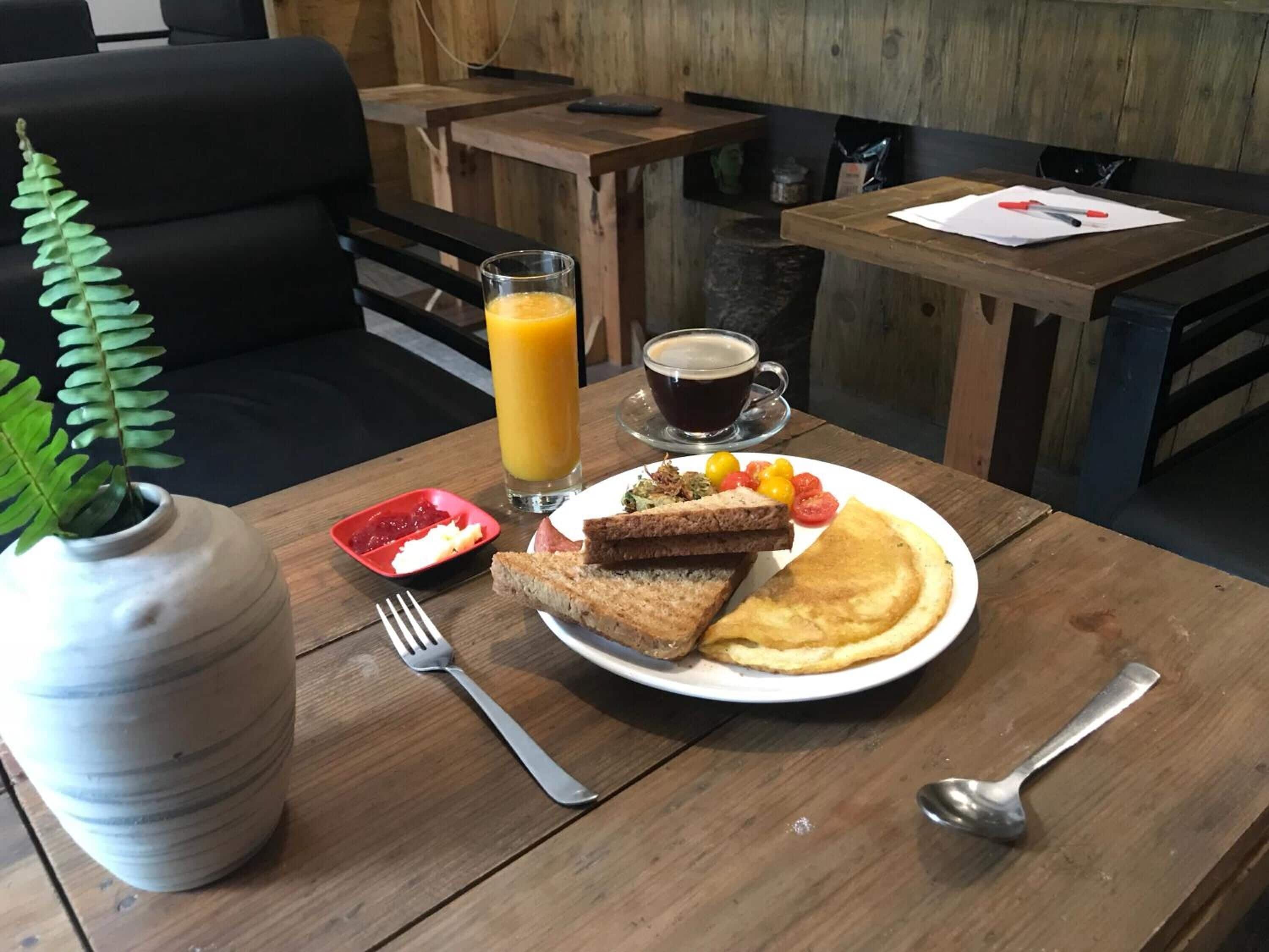 Ein Frühstückstisch mit Toast, Eiern, Obst, einem Glas Orangensaft und einer Tasse Kaffee.