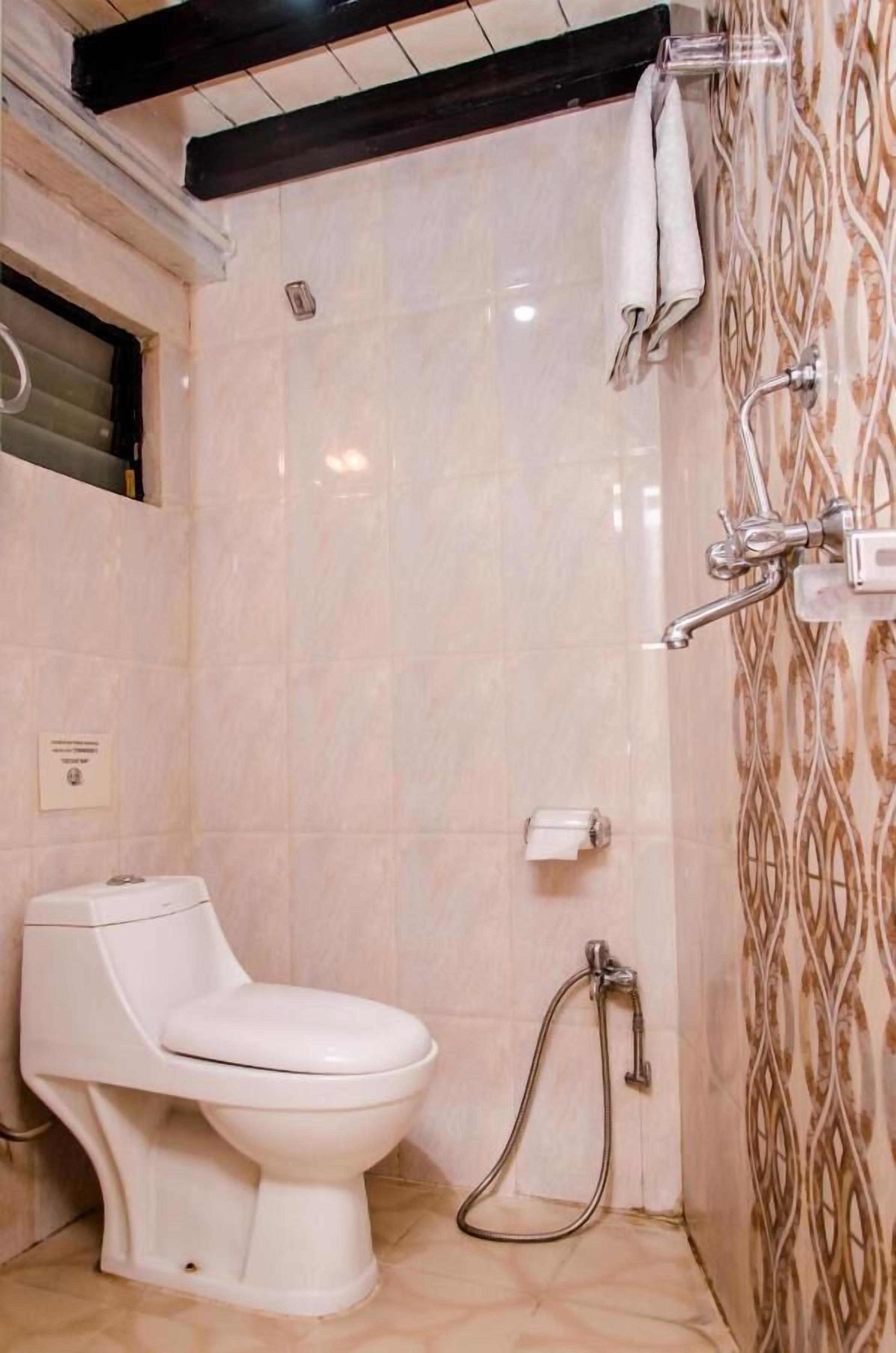 A bathroom with a toilet, a shower, and a patterned wall.
