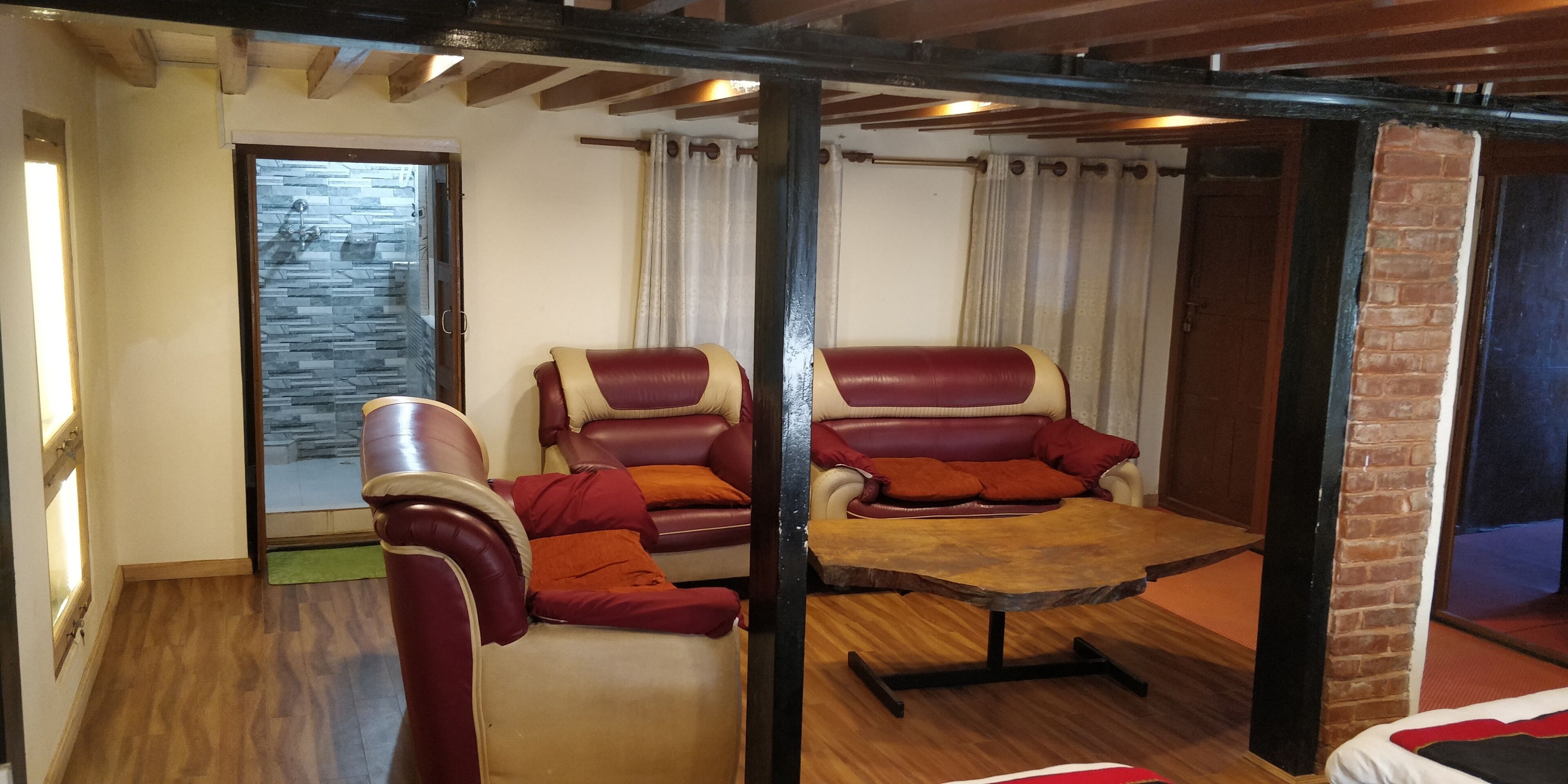 A room with two leather chairs, a wooden table, and a brick wall.