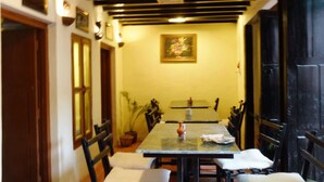 A dining area with a table and chairs, a potted plant, and a painting on the wall. - Tulaja Boutique Hotel (Bhaktapur)