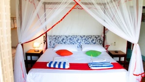 A bed with a canopy, pillows, and a bedside table with a lamp. - Feel Beach Apartments (Kalutara)