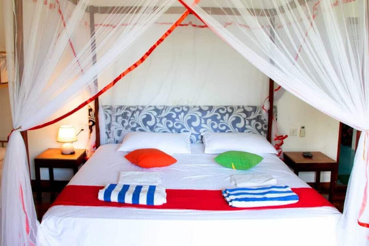 A bed with a canopy, pillows, and a bedside table with a lamp.