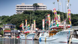 A harbor with several boats docked, surrounded by buildings and a hill in the background. - Hagi Kanko Hotel (Hagi)