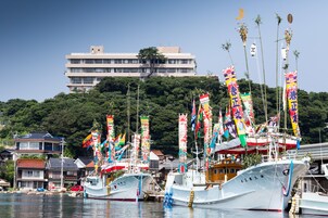 Un puerto con varias embarcaciones amarradas, rodeado de edificios y una colina al fondo.