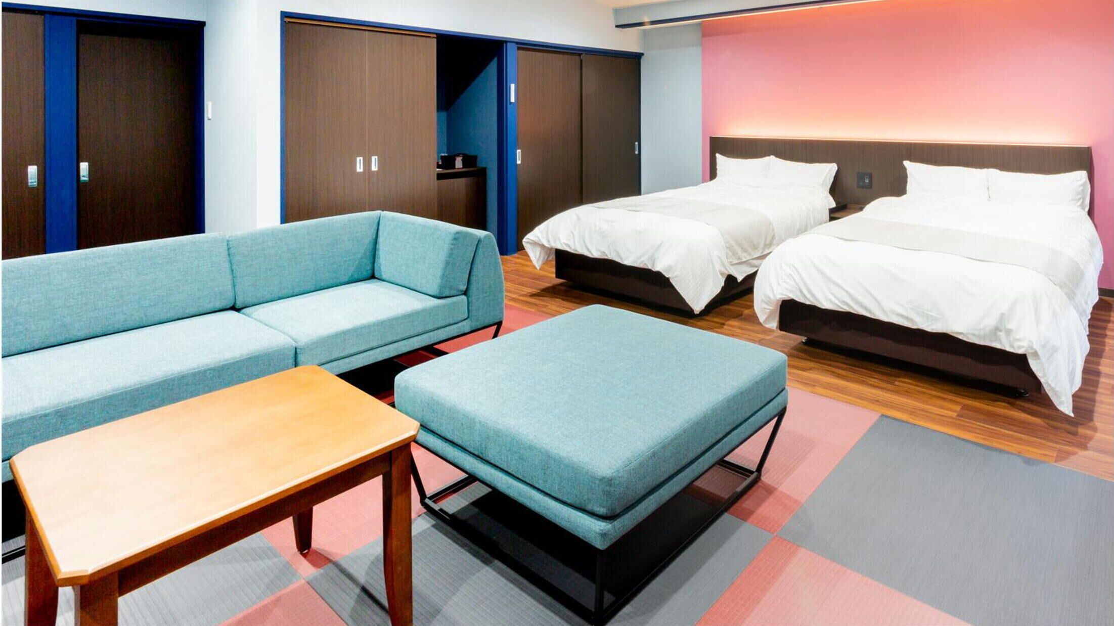 Una habitación de hotel con sofá, dos camas, una mesa y un armario.