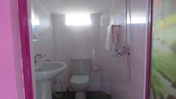A small, compact bathroom with a white sink, toilet, and shower.