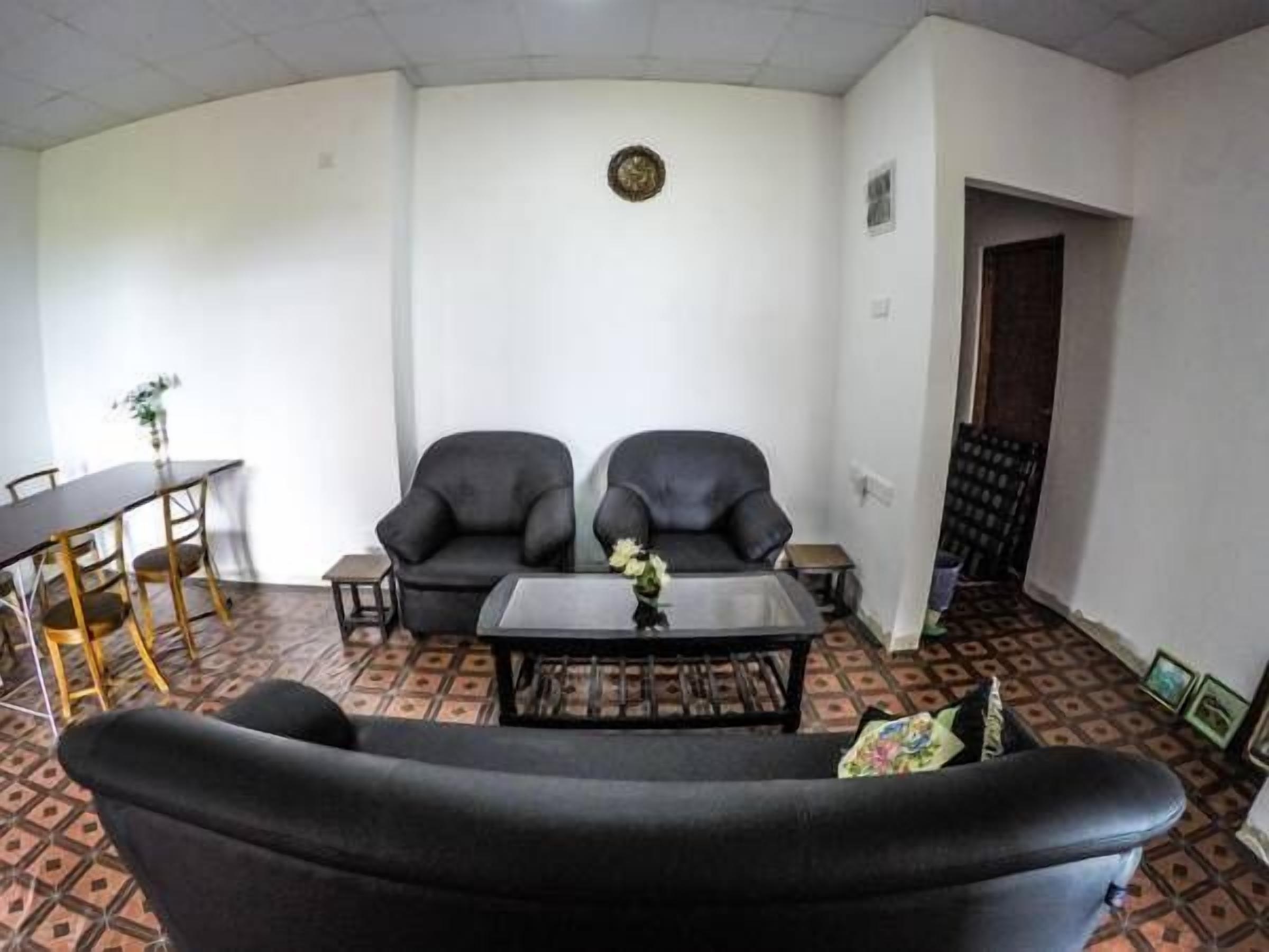 A living room with two black armchairs, a small coffee table, and a dining table with chairs.