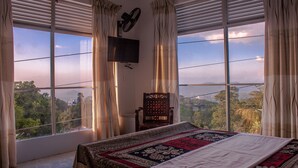 Un dormitorio con una cama grande, una silla y un televisor en la pared.