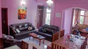 Una sala de estar con dos sofás de cuero marrón oscuro, una mesa de centro de madera y una mesa de comedor con sillas.