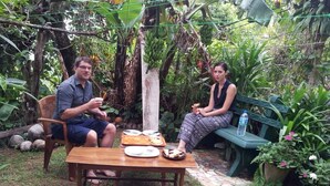 Dos personas cenando en una mesa al aire libre, con una palmera en el fondo.