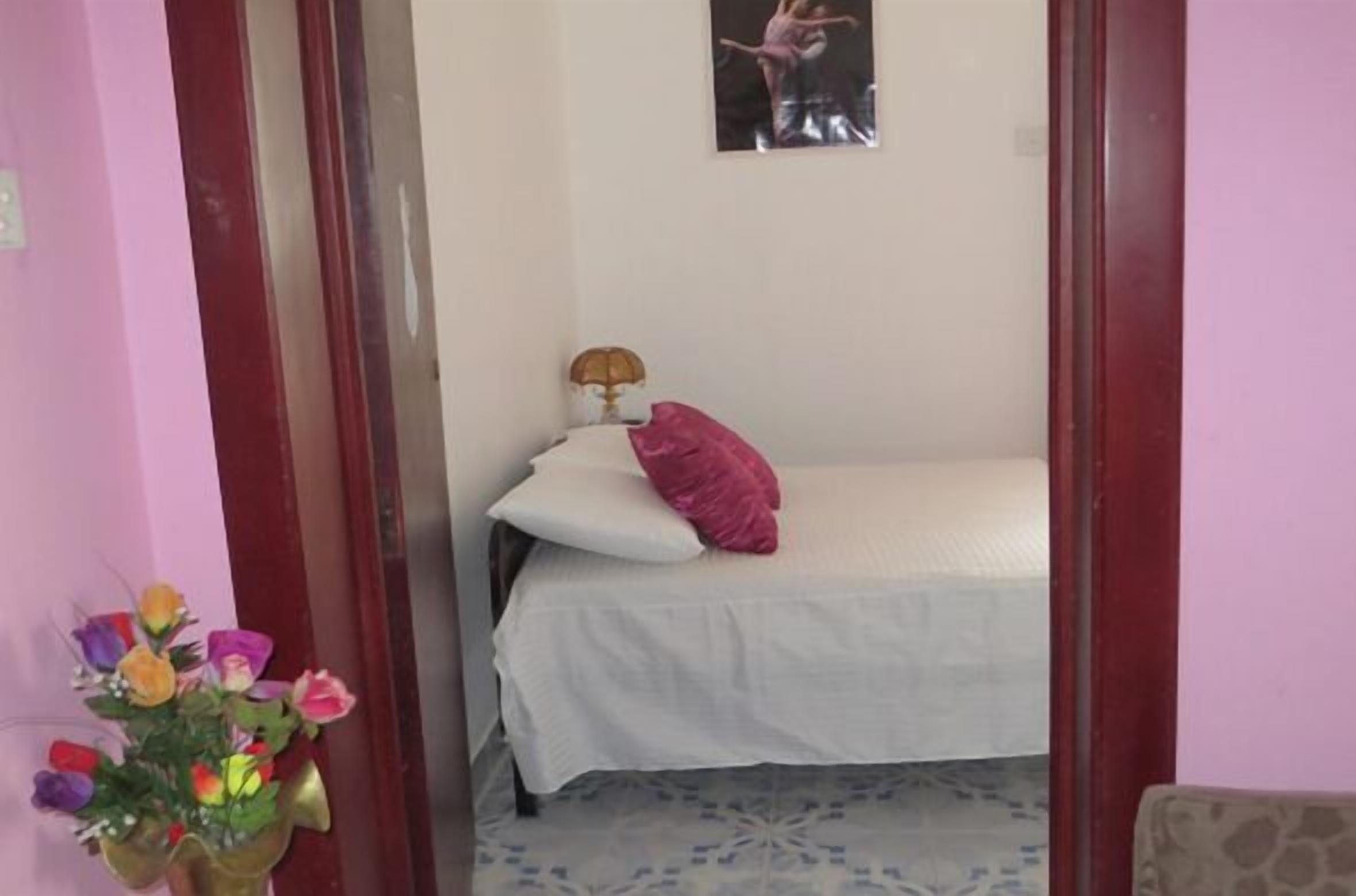 A bedroom with a bed, a nightstand, a lamp, and a poster on the wall.