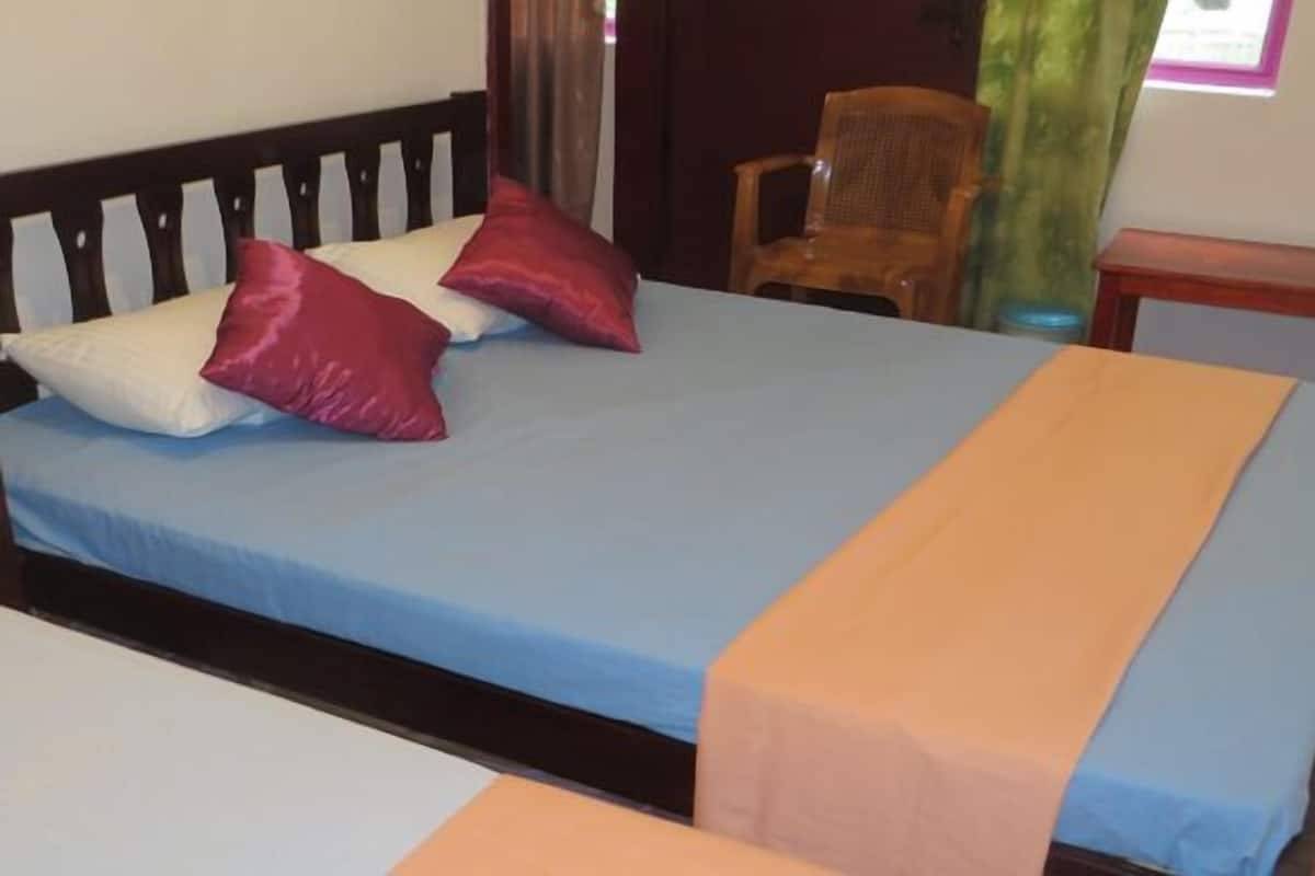 Ein Bett mit blauer Matratze und zwei Kissen, eines weiß und eines rot, in einem Zimmer mit Holz-Kopfteil.