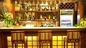 Een bar met houten stoelen, diverse flessen en een koelkast.