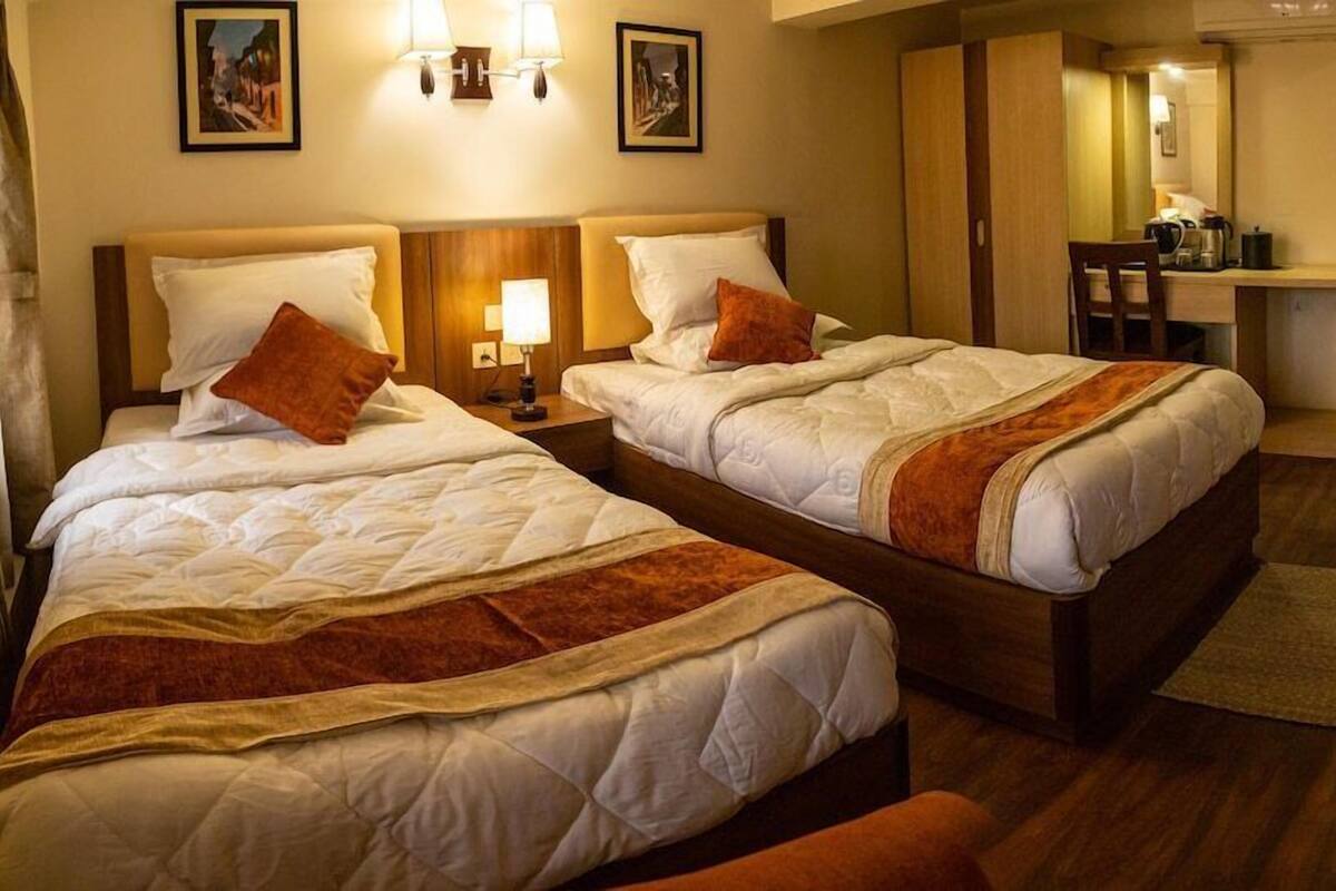A hotel room with two beds, a desk, and a chair.