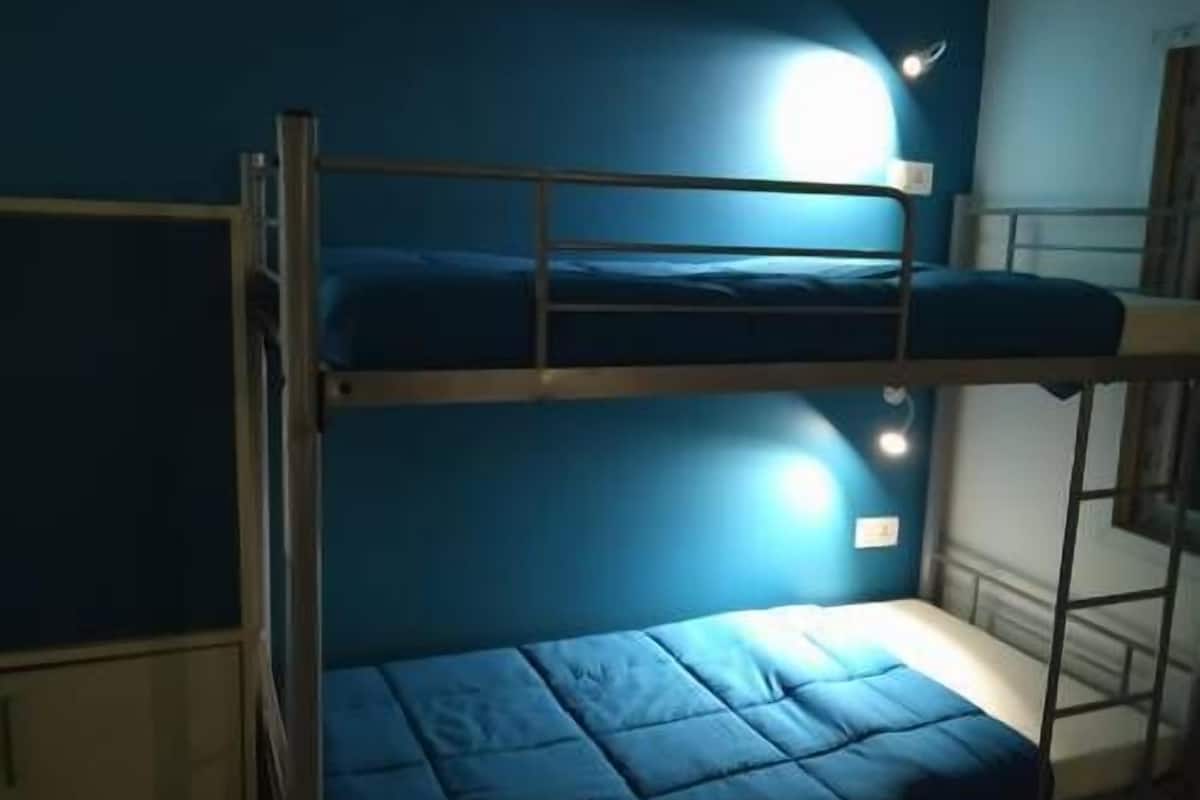 Ein Schlafzimmer mit Etagenbetten, blauer Wand und kleinem Fenster.
