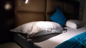 A bed with a headboard, white pillows, and a blue blanket.