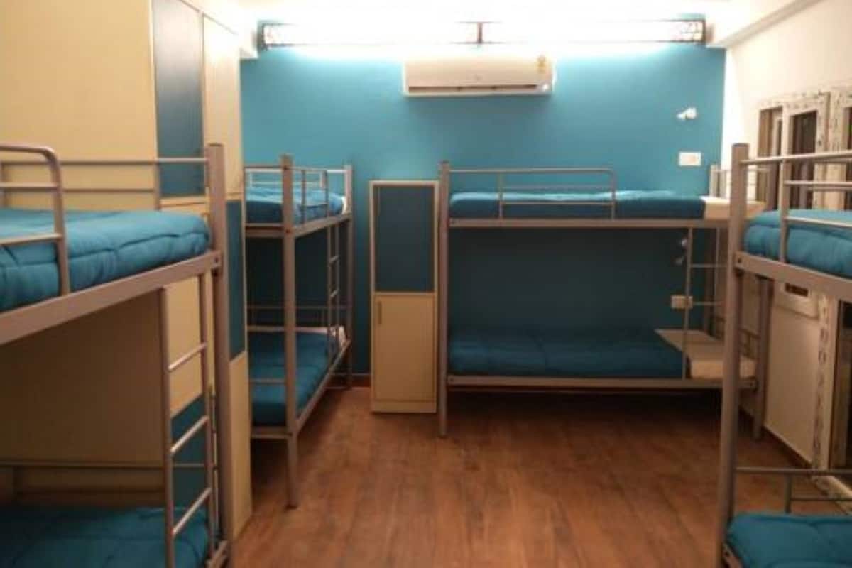 Ein Schlafsaalzimmer mit Etagenbetten, einem kleinen Schrank und einer Klimaanlage an der Wand.