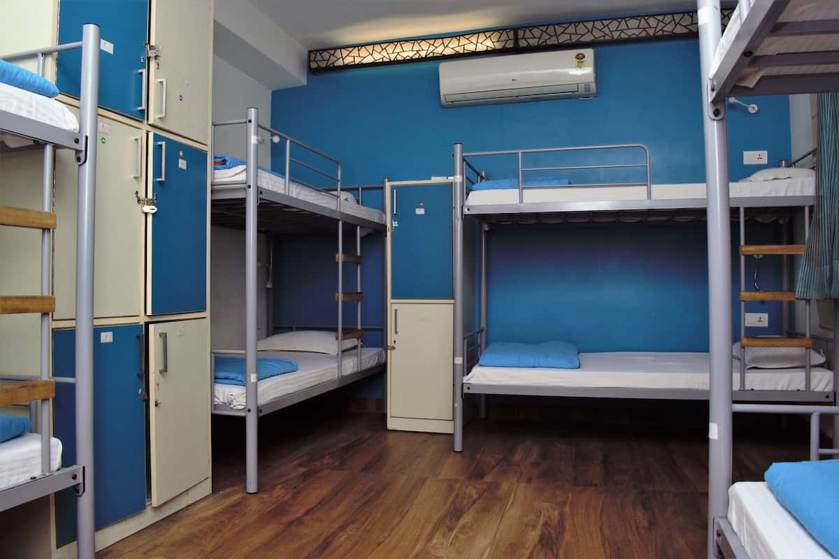 Ein Schlafsaalzimmer mit Etagenbetten, einem Kleiderschrank und einer Klimaanlage.