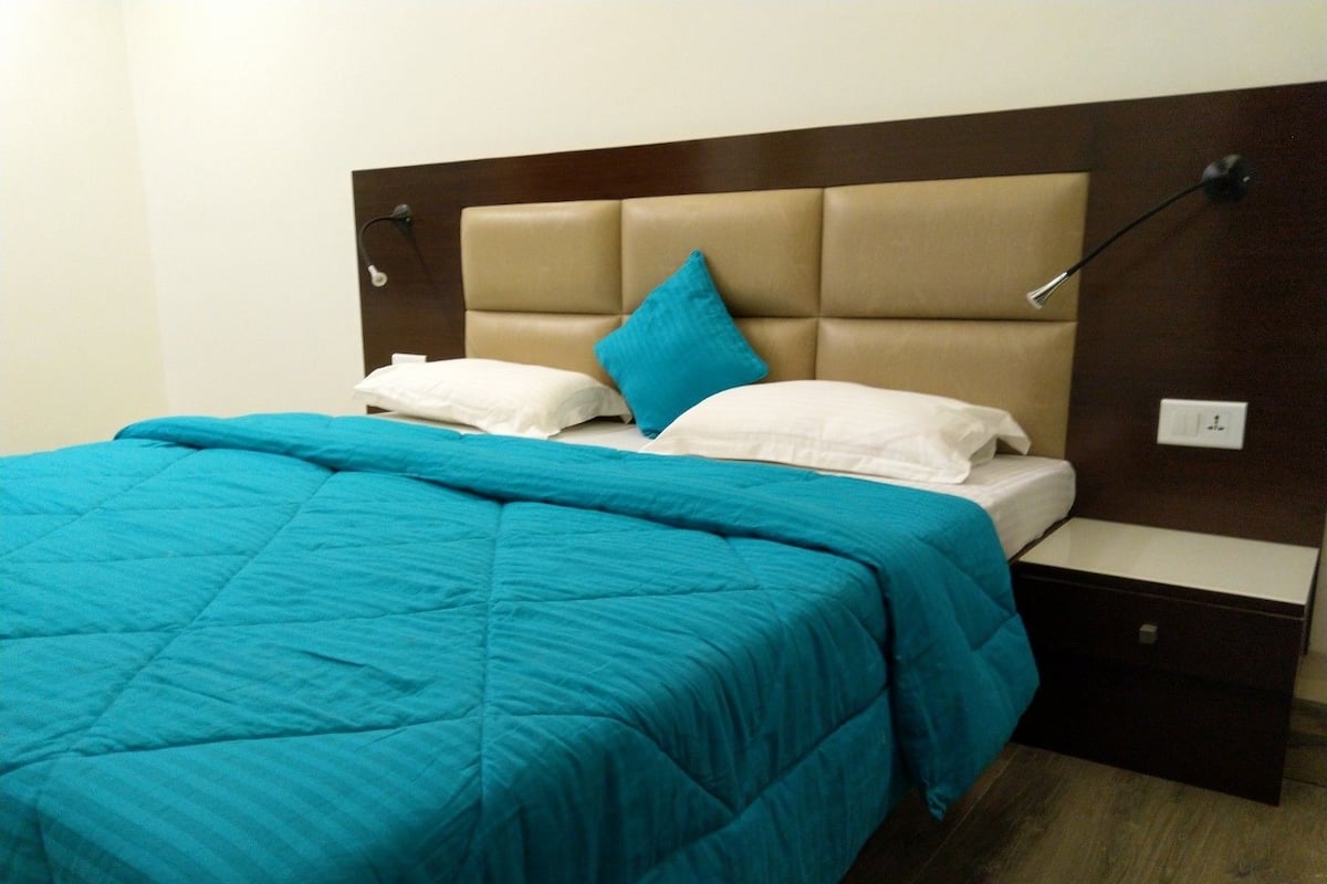 Ein Bett mit himmelblau gestreifter Bettdecke, weißen Kissen und einem braunen Kopfteil.