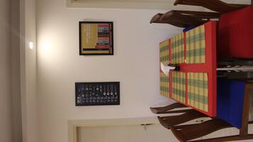 A dining area with a table set for four, surrounded by wooden chairs. There are two framed items on the wall above the table.
