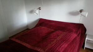 Een kamer met een bed, twee wandlampen en een witte nachtkastje.
