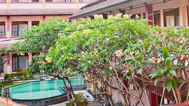 A traditional building with a swimming pool and lush greenery. - Pesona Beach Inn (Kuta)