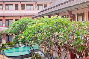 Un edificio tradicional con piscina y abundante vegetación.