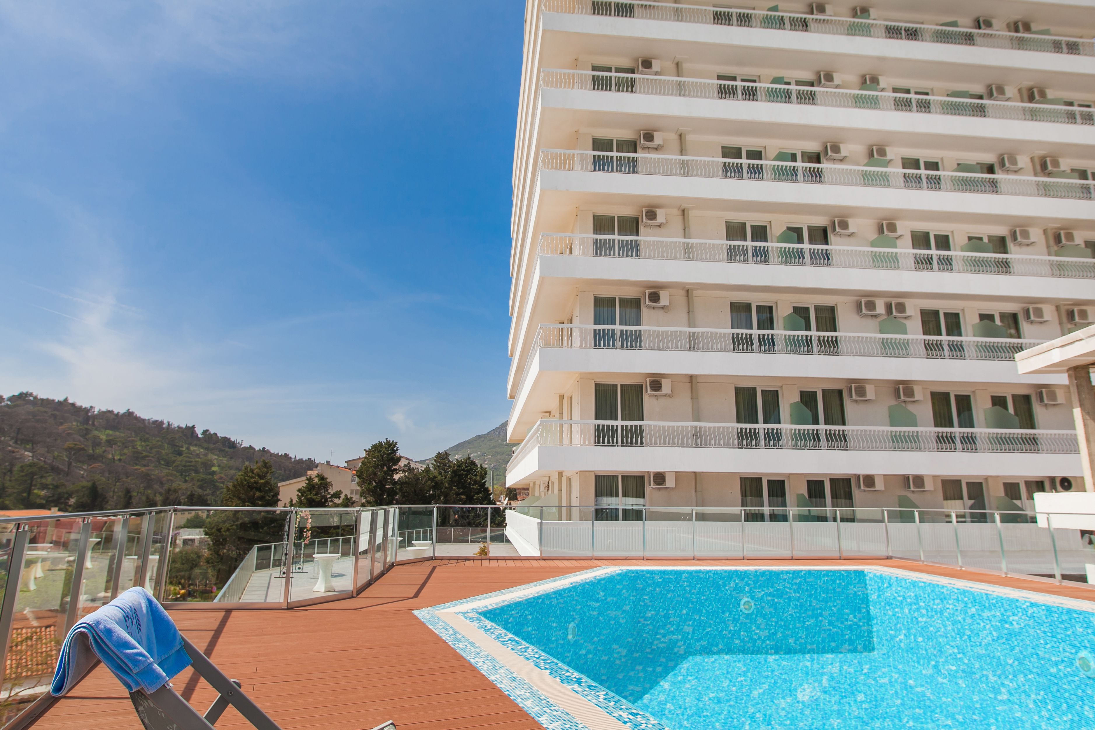 Una piscina en la azotea con vistas despejadas a un edificio de varios pisos con balcones y unidades de aire acondicionado.