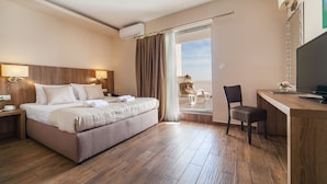 A hotel room with a bed, a desk, a chair, an air conditioner, and a TV. - Hotel Sato (Sutomore)