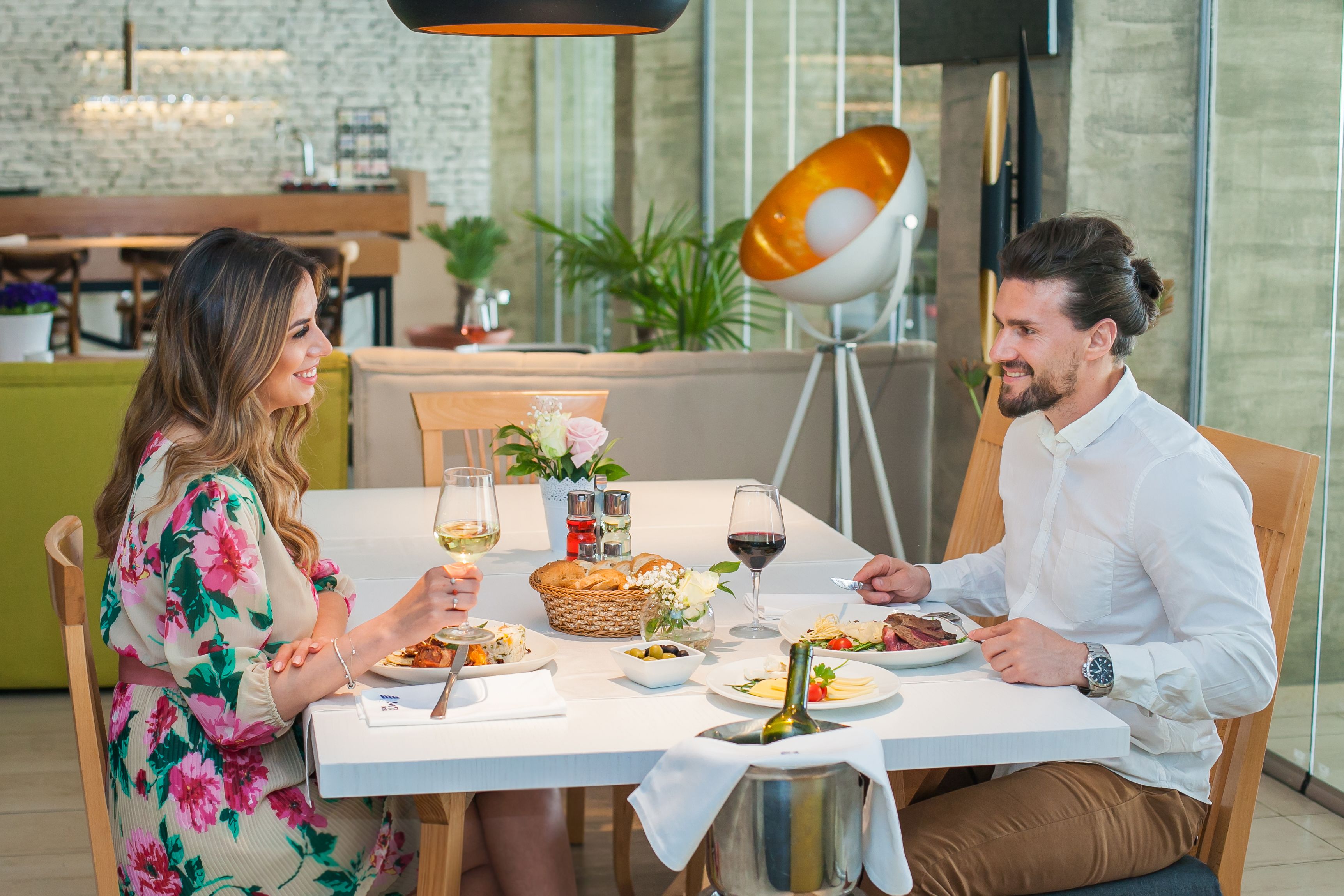 Een eettafel met borden eten, wijnglazen en een wijnfles.